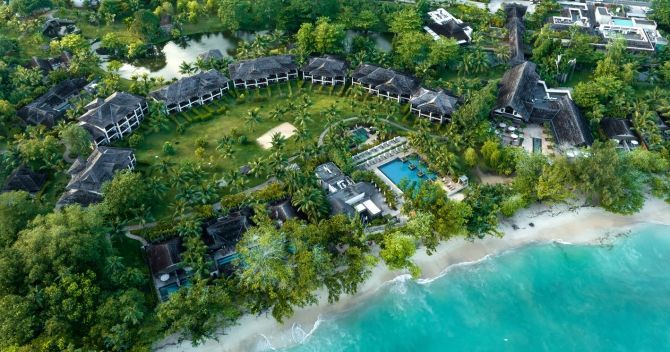 Bird's-eye view of the expansive Story Seychelles resort, with its beachfront location, thatched-roof structures, and lush surroundings on Mahe Island.