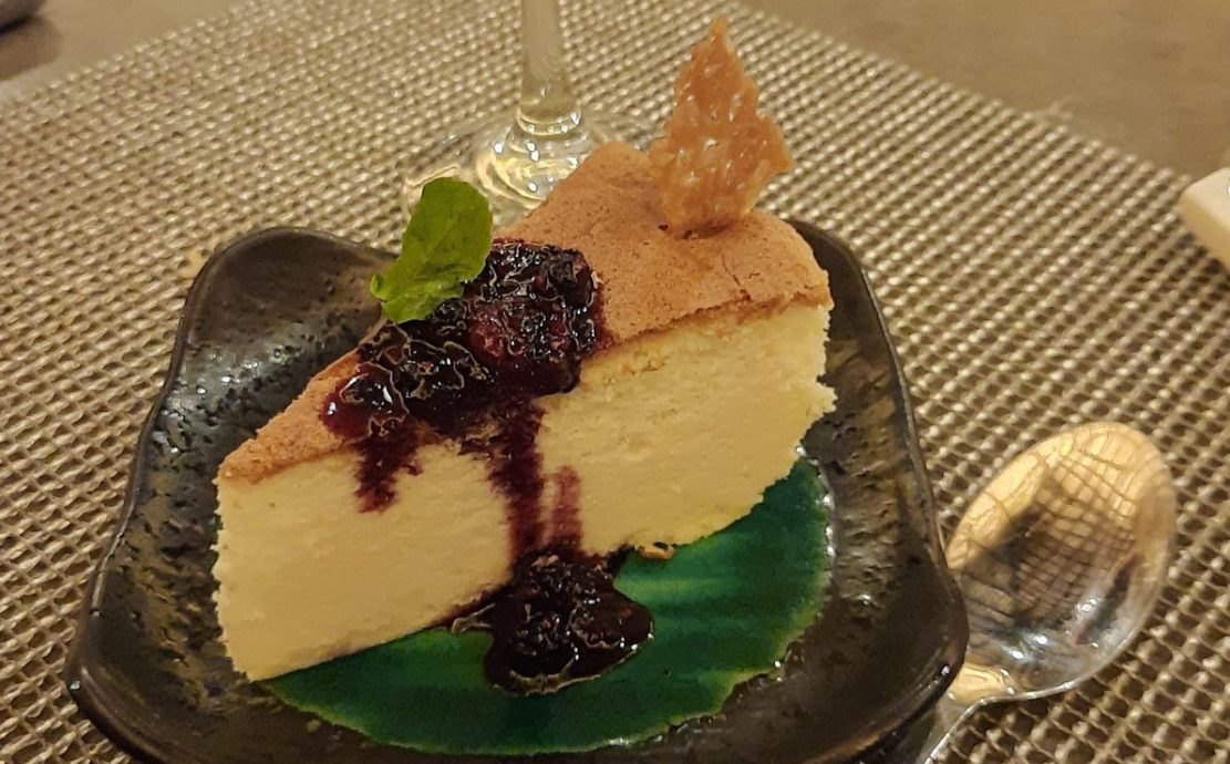 Cheesecake with berry compote accompanied by a glass of red wine.