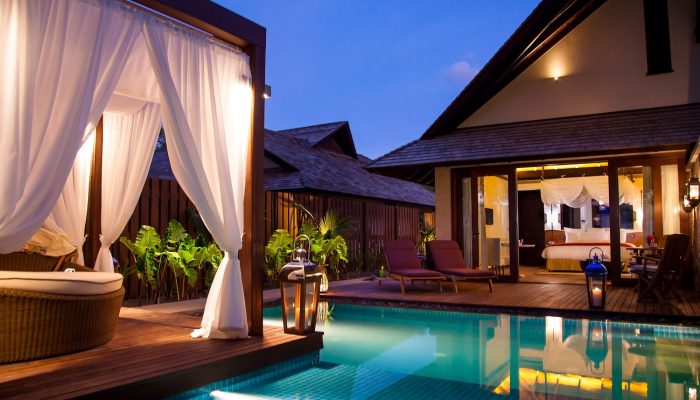 Luxurious private pool villa at a Seychelles resort during dusk, with soft lighting and a four-poster daybed.