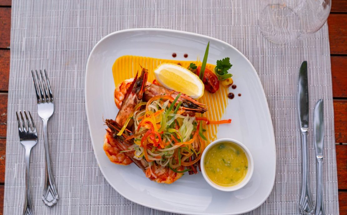 Freshly prepared prawn dish with colorful garnish and sauce, ready to be enjoyed at Eden restaurant in Mahe.