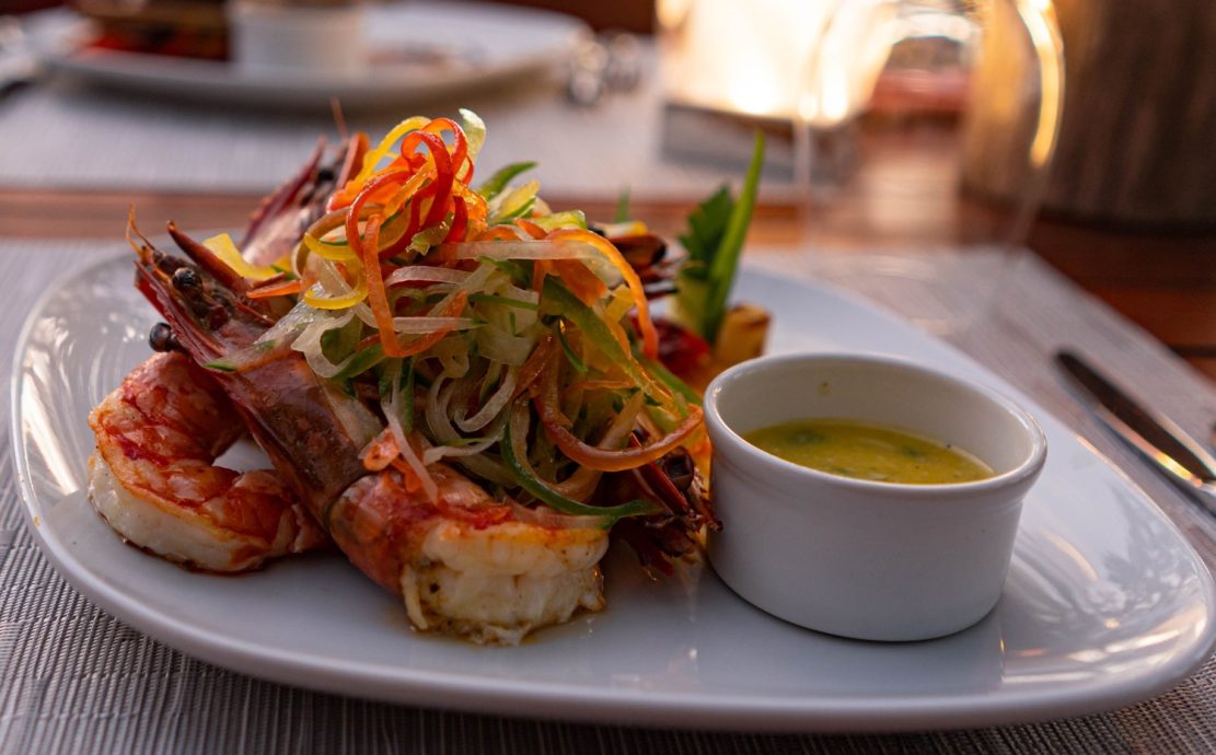 Gourmet grilled prawns with vegetables and dipping sauce, served at Story Seychelles Mahe resort restaurant.