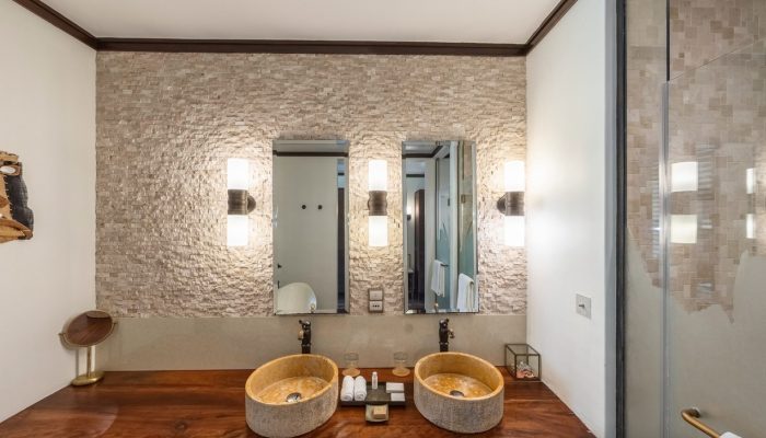 Spacious bathroom interior featuring double stone basins, a large mirror, and a glass-enclosed shower.