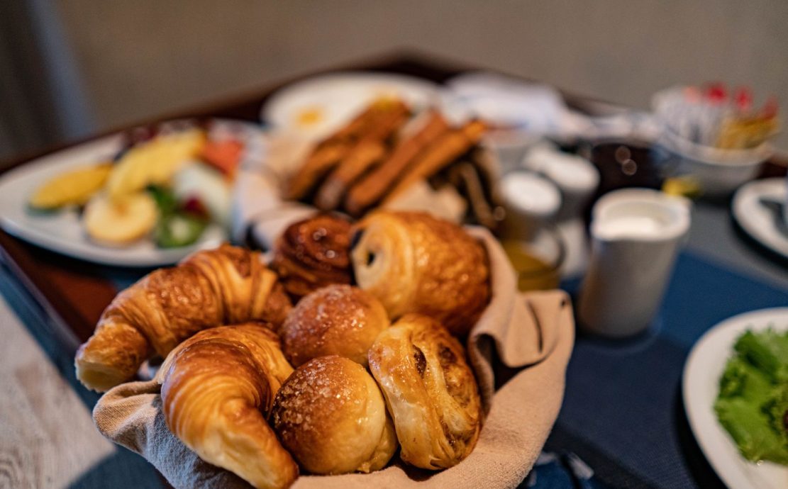 A basket of freshly baked croissants and pastries on a breakfast tray.