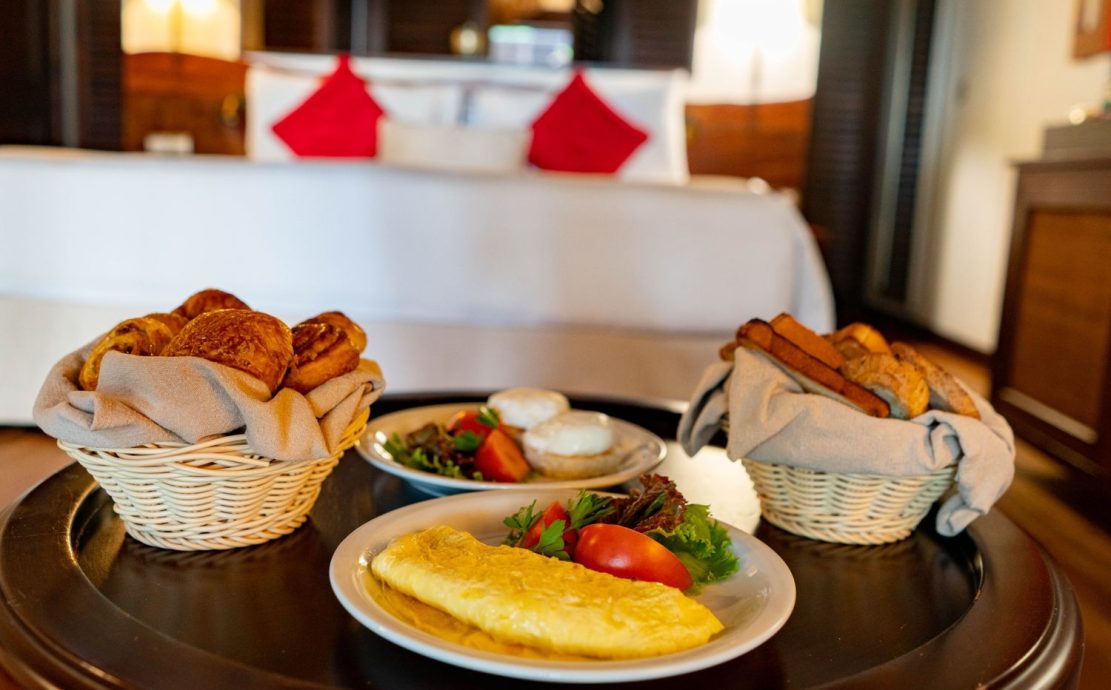 Omelet, fried eggs, and baskets of pastries on a breakfast table.