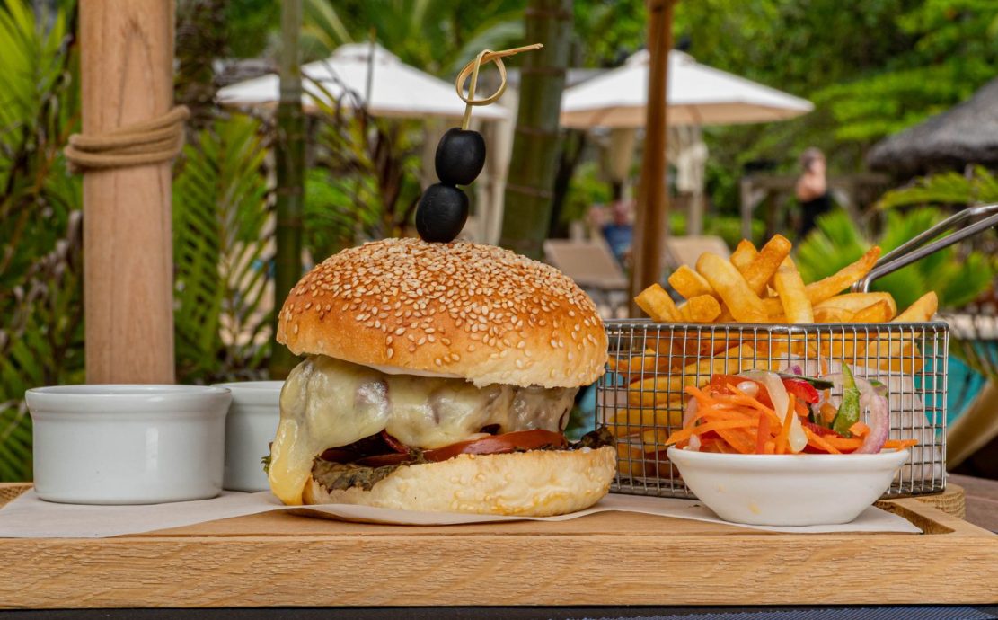 Gourmet cheeseburger with fries and salad served poolside at a Seychelles resort restaurant.