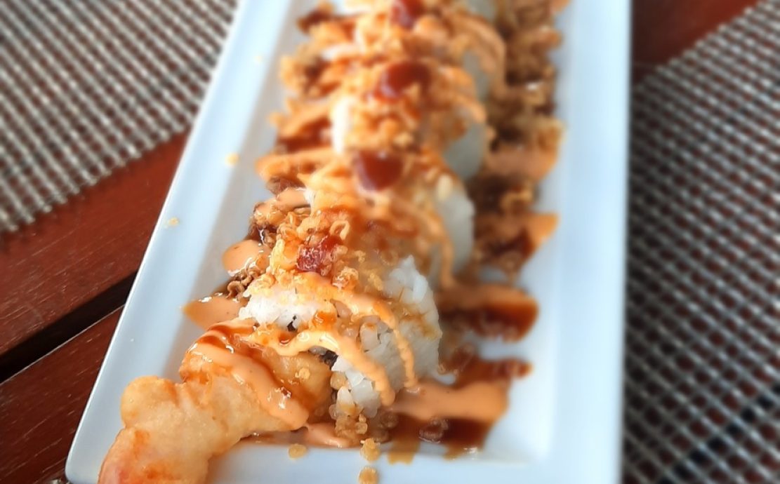 Long sushi rolls with crispy topping on a narrow plate at an oriental Seychelles restaurant.