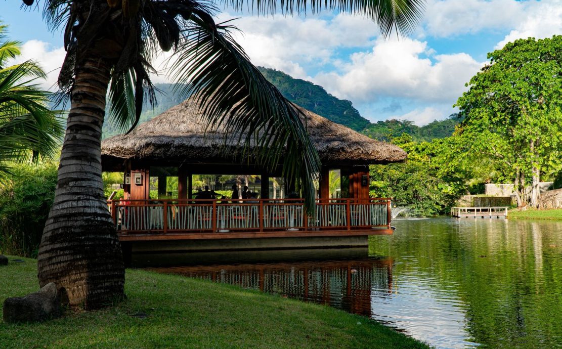 Tranquil riverside restaurant with a thatched roof in the Seychelles Islands.