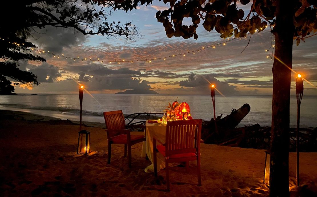 Romantic dinner setting on the beach with candles at Story Seychelles, Mahe Island.