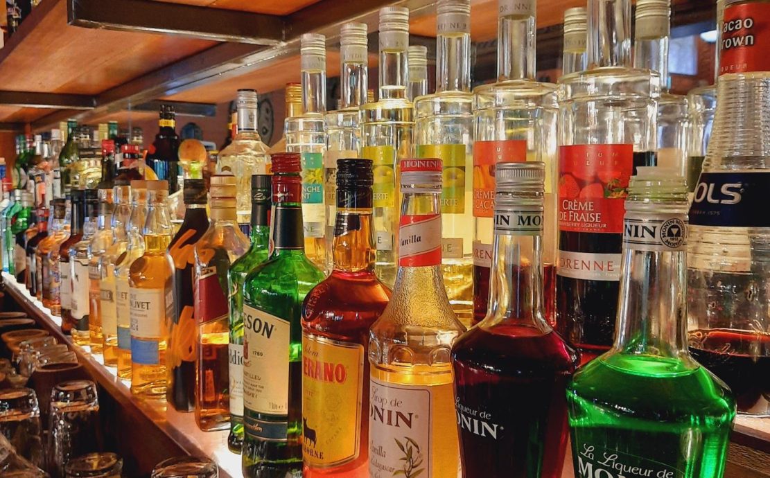Assortment of liquor bottles on a bar shelf, offering a variety of flavors for crafted cocktails at a Seychelles resort.