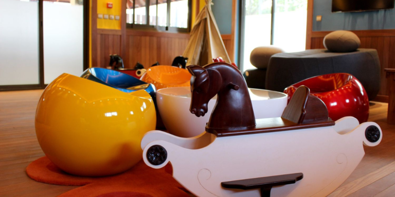 Close-up of playful children's rocking toys and colorful egg chairs.