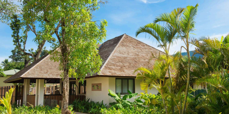 Luxury villa with thatched roof amidst tropical gardens in a Seychelles luxury resort on Mahe Island.