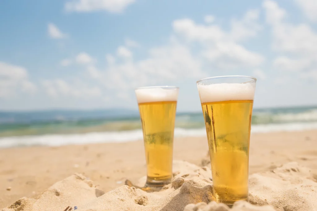 Two glasses of beer on the beach.