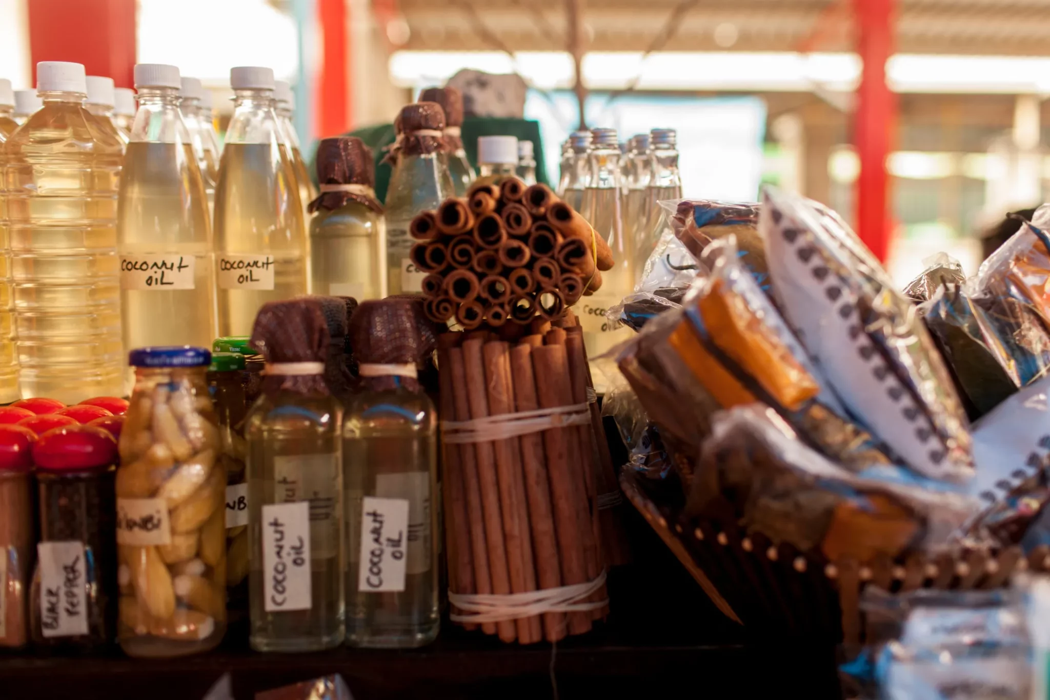 A variety of local Seychelles products on display at a Seychelles market, including bottles of coconut oil and bundles of cinnamon sticks.
