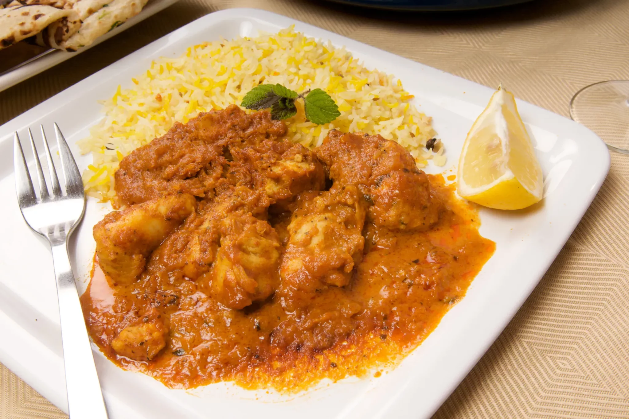 Spicy chicken curry served alongside fragrant saffron rice, garnished with a wedge of lemon, a fusion of flavors often found in Seychelles cuisine.