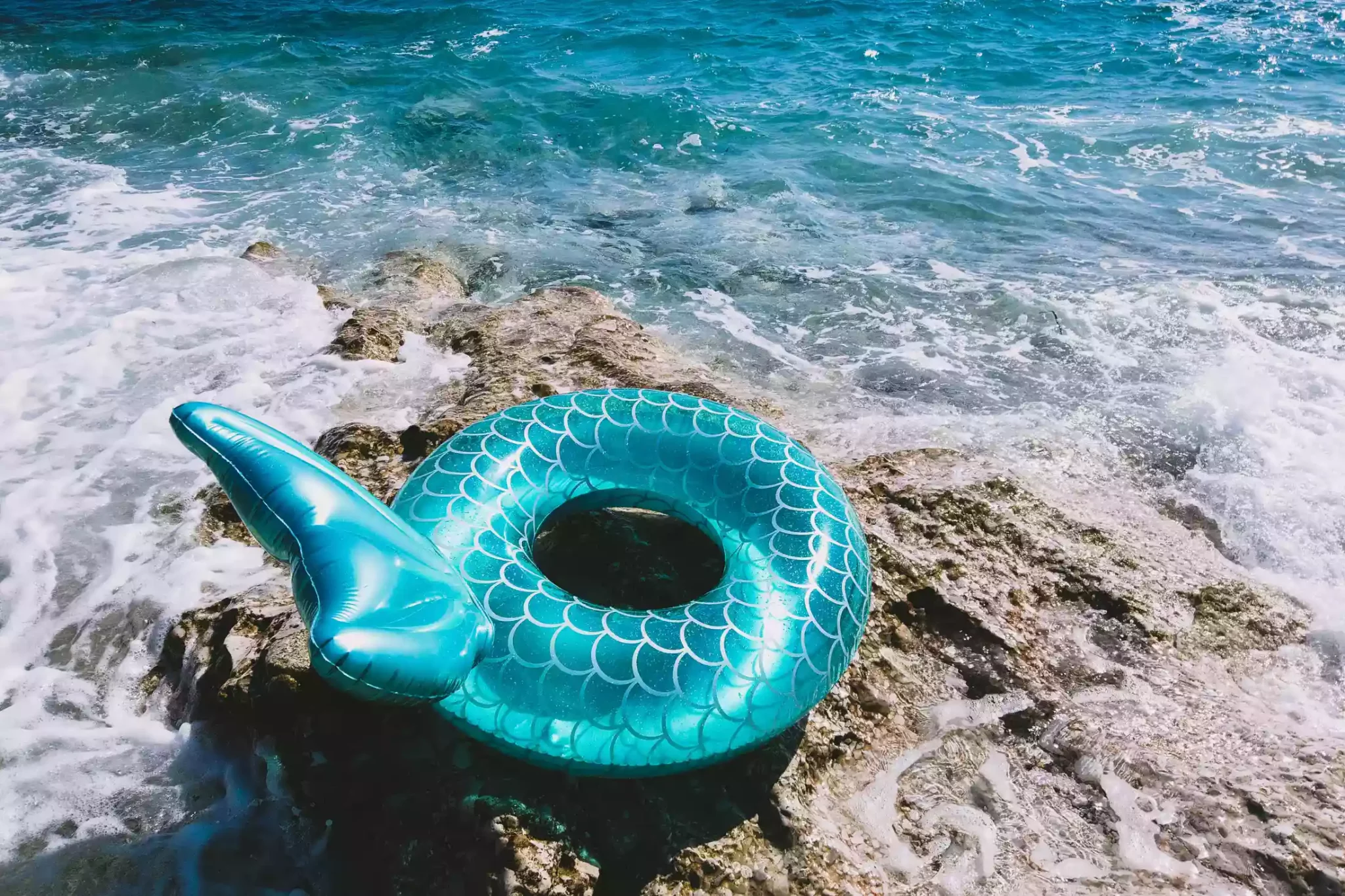 Inflatable Pool Ring with Mermaid Tail on the Rocks.