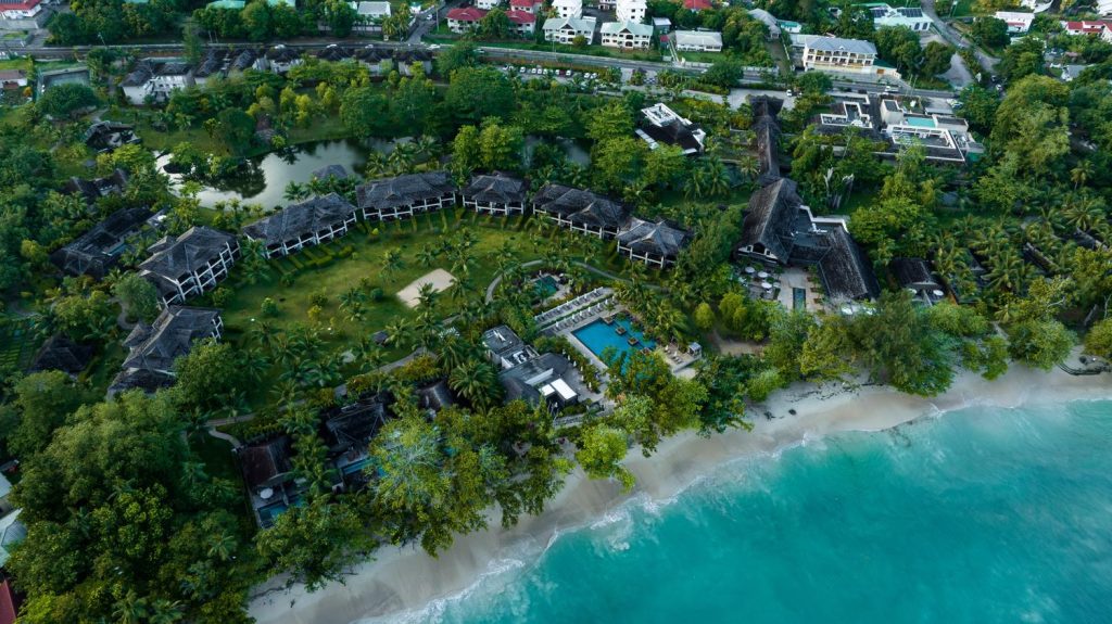 Bird's-eye view of the expansive Story Seychelles resort, with its beachfront location, thatched-roof structures, and lush surroundings on Mahe Island.