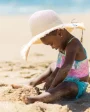 small child playing on a beach in the sand