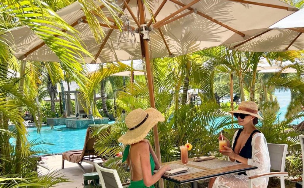 Women enjoying refreshing drinks at a poolside table of the 5 star mahe resort Story Seychelles.