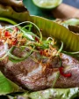 Traditional Seychelles cuisine featuring a freshly prepared fish wrapped in banana leaves, garnished with spices and herbs.