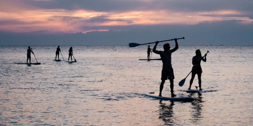 Paddle boarders on the calm sea at sunset in the Seychelles.