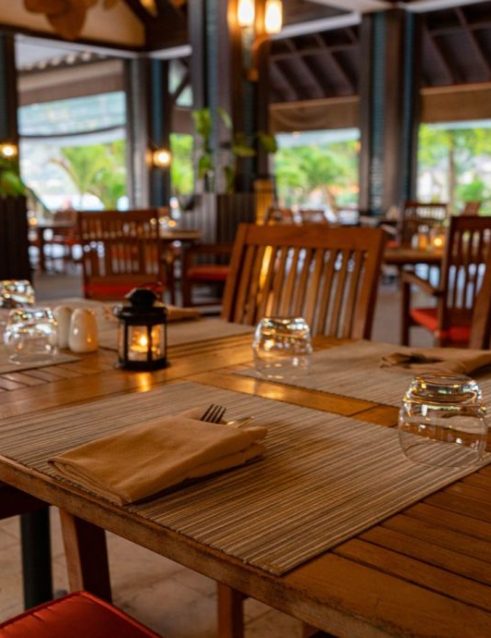 Seychelles restaurant interior with wooden tables and warm ambiance, ready to welcome guests at the Story Seychelles resort.