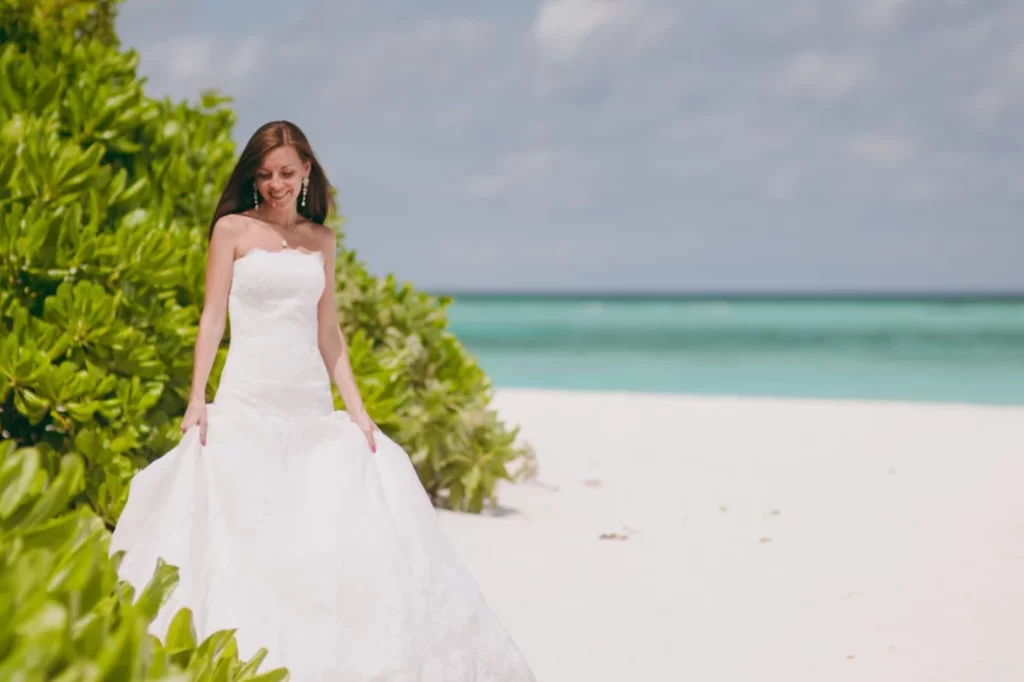 A woman on the beach wearing a weeding dress.