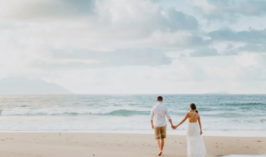 A couple walking along a Seychelles beach.