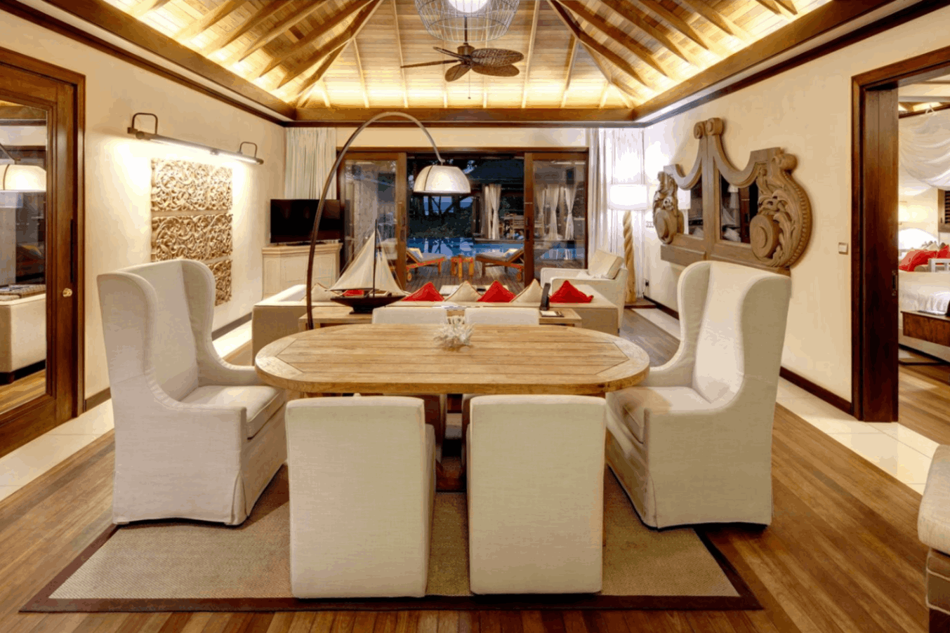 Elegant dining area inside a Seychelles luxury resort, with white upholstered chairs and wooden interior design.