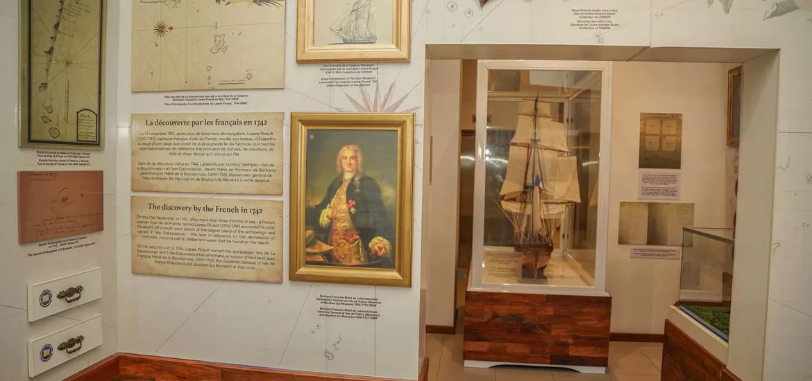 Seychelles National History Museum exhibit displaying historical maps, artifacts, and a model ship related to French exploration.