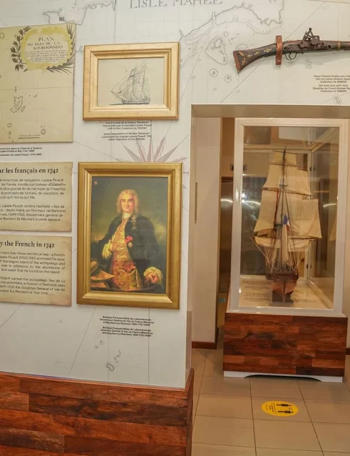 Seychelles National History Museum exhibit displaying historical maps, artifacts, and a model ship related to French exploration.