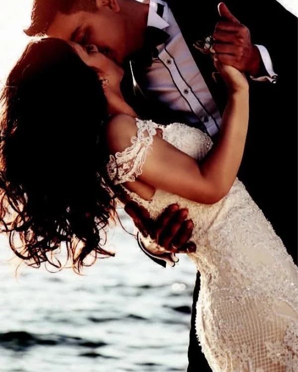 A bride and groom in a romantic beach embrace at sunset, capturing a special moment.